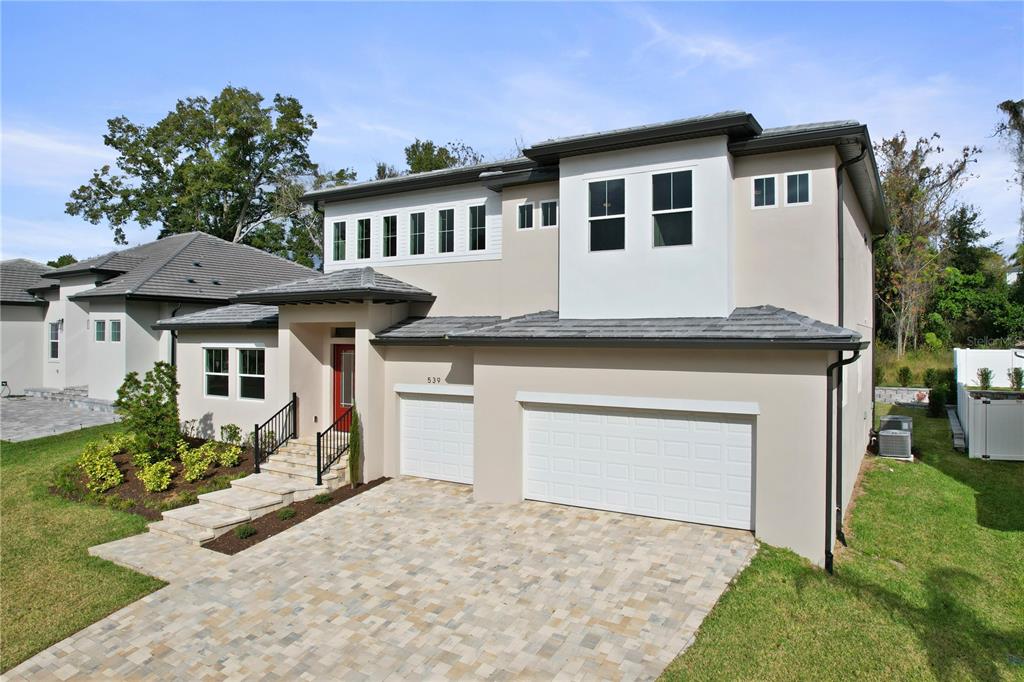 A two-story house with a beige stucco exterior, a three-car garage, and a paved driveway — 539 SANCTUARY GOLF PLACE, APOPKA, FL