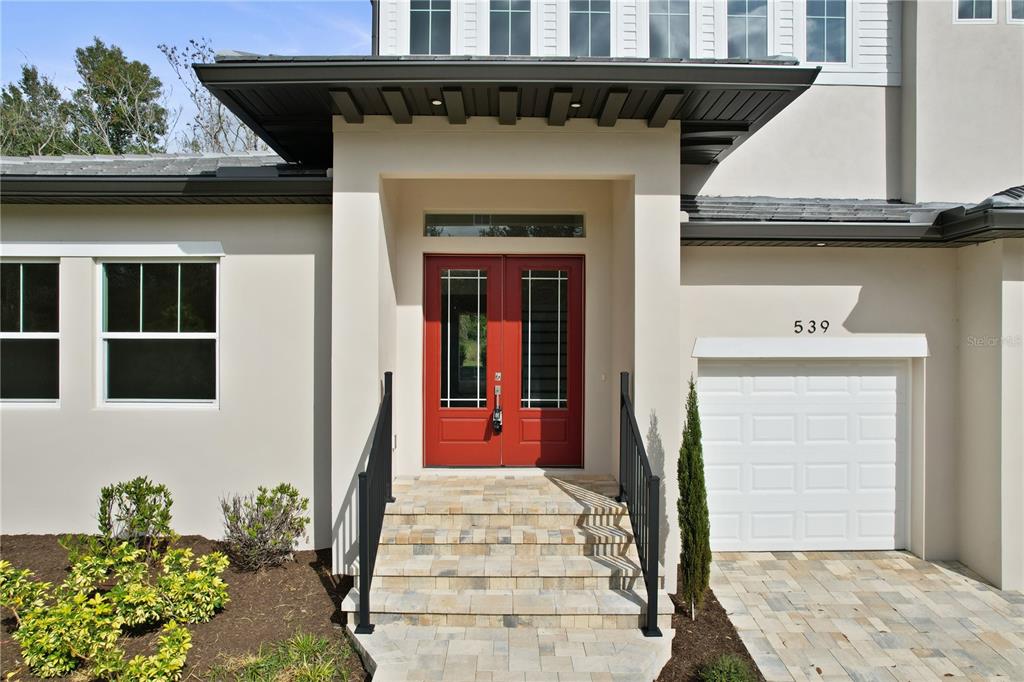 The exterior of a house features a red double front door and a garage — 539 SANCTUARY GOLF PLACE, APOPKA, FL