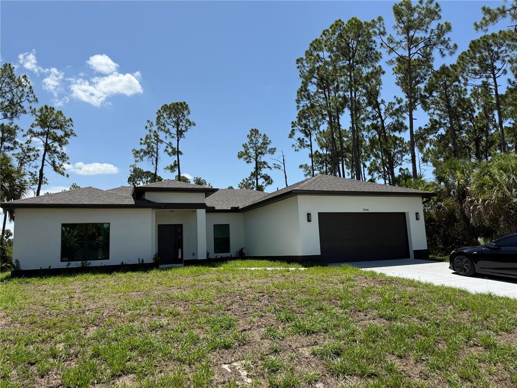 A modern, single-story house with a dark garage door and white stucco exterior — 2646 SADNET LANE, NORTH PORT, FL