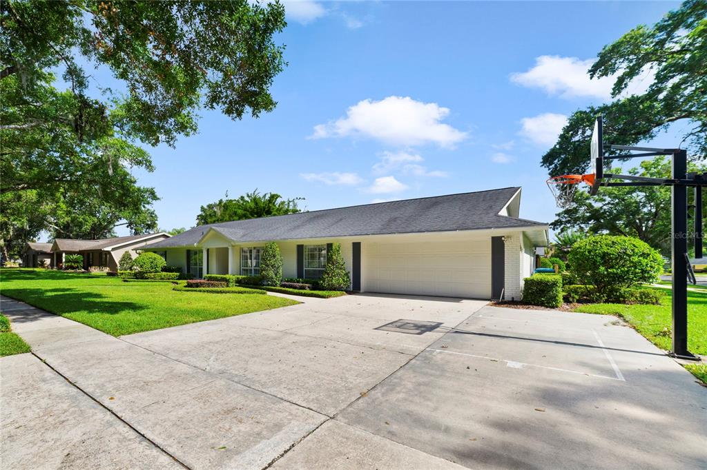 A single-story house with a white exterior, a two-car garage, and a basketball hoop — 1615 KING ARTHUR CIRCLE, MAITLAND, FL