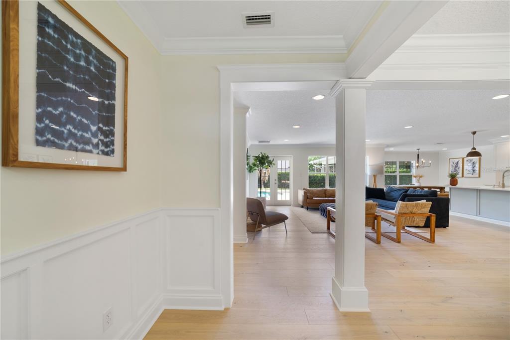 A view through a white-trimmed doorway into an open-concept living area with light wood floors — 1615 KING ARTHUR CIRCLE, MAITLAND, FL