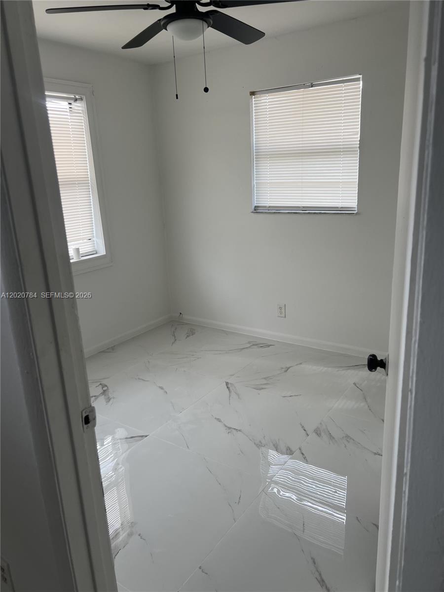 A small bedroom features white walls, a ceiling fan, and white marble-patterned tile flooring — 4809 SW 25th St, West Park FL 33023, WEST PARK, FL
