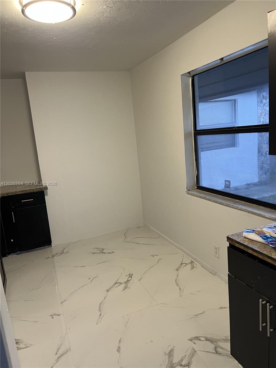 This kitchen features white marble-look tile flooring, black cabinets, and a window — 4809 SW 25th St, West Park FL 33023, WEST PARK, FL