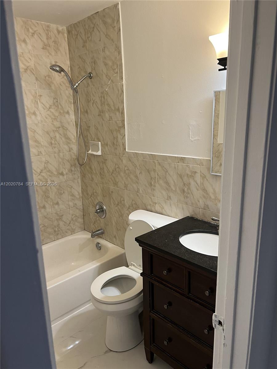 A small bathroom features a bathtub with a showerhead, a toilet, and a dark vanity — 4809 SW 25th St, West Park FL 33023, WEST PARK, FL