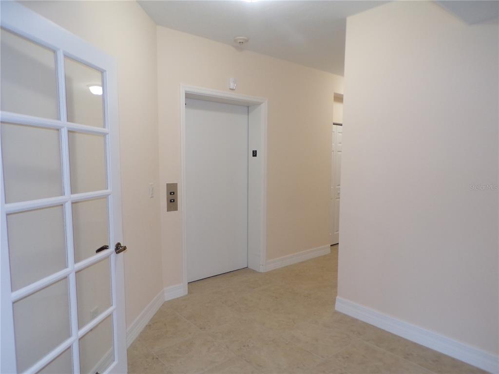 A hallway features a white elevator door, tile flooring, and a glass-paneled door — 93 VIVANTE BOULEVARD UNIT 9333, PUNTA GORDA, FL