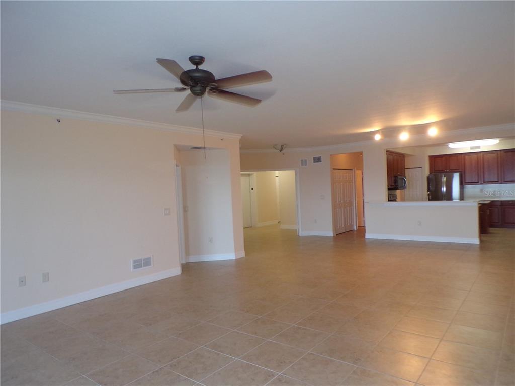 An open-concept living area features beige tile floors, a ceiling fan, and an adjacent kitchen — 93 VIVANTE BOULEVARD UNIT 9333, PUNTA GORDA, FL