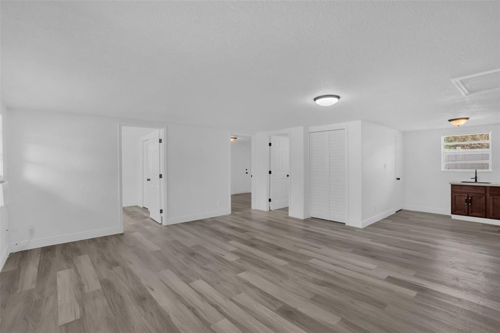 A bright, open-concept room features white walls, light wood-look flooring, and several interior doors — 1460 MARVIN C ZANDERS AVENUE UNIT A, APOPKA, FL