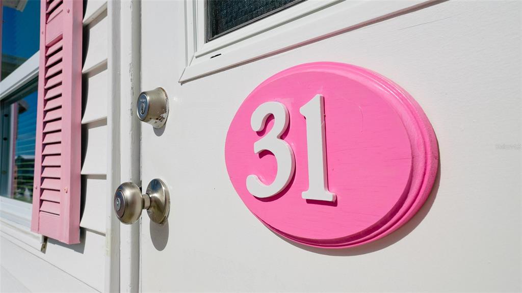 A white door features a pink oval plaque with the number 31 and pink shutters — 10315 CORTEZ ROAD W UNIT 31-1, BRADENTON, FL
