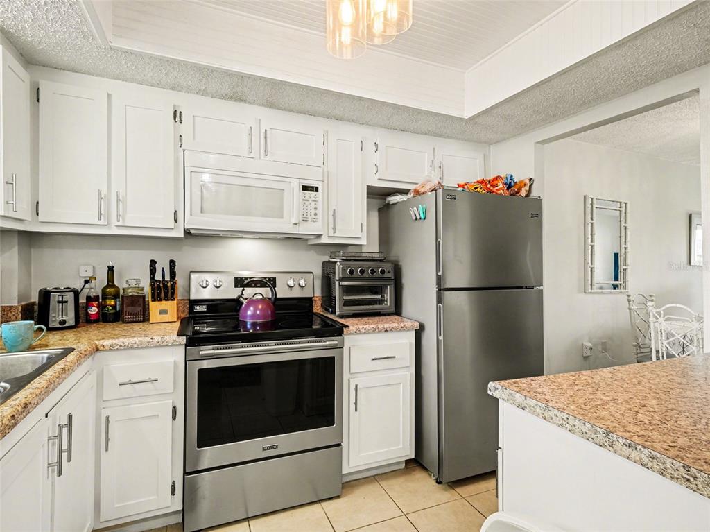 A hallway with tiled floors, two wall-mounted mirrors, and a view into a living area — 3915 LAKE BAYSHORE DRIVE UNIT 306, BRADENTON, FL