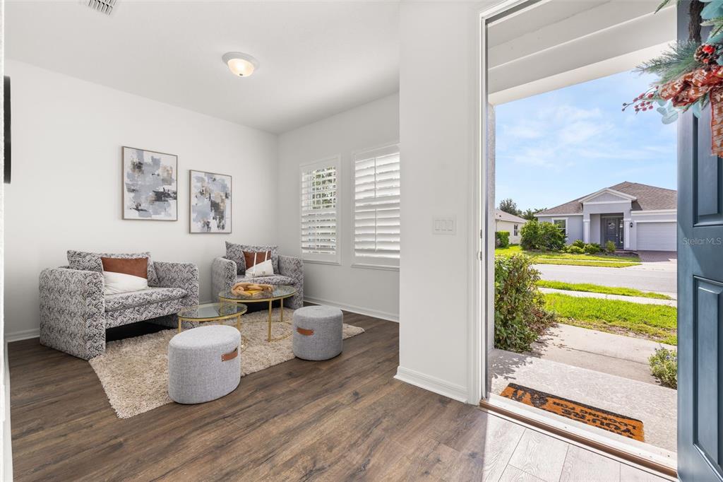 A bright entryway features wood-look flooring, two patterned armchairs, and a view of the neighborhood — 2933 DEERBERRY LANE, CLERMONT, FL