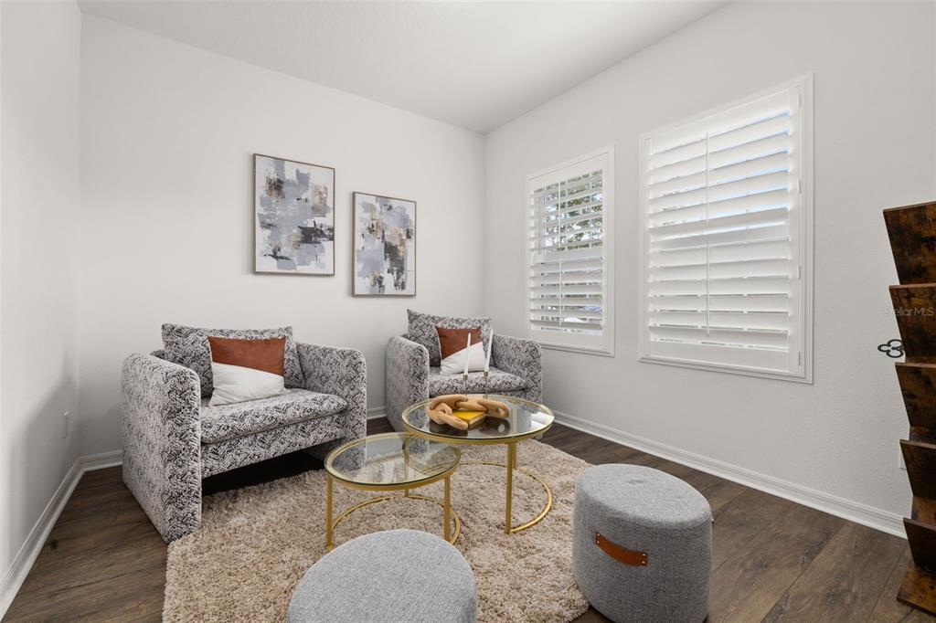A sitting room features two patterned armchairs, two ottomans, and a glass-topped nesting coffee table — 2933 DEERBERRY LANE, CLERMONT, FL