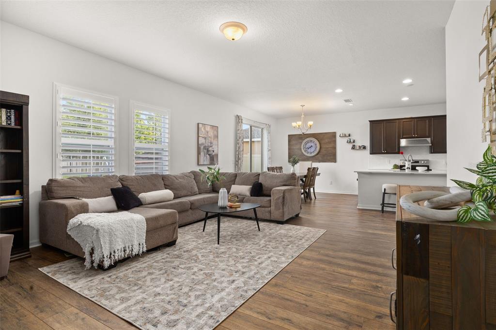 An open-concept living room features a sectional sofa, area rug, and an adjacent kitchen — 2933 DEERBERRY LANE, CLERMONT, FL