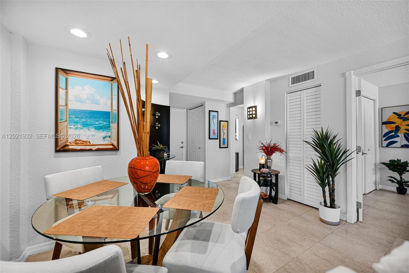 A dining area features a glass table, four chairs, and a large ocean-view wall art — 1334 Collins Ave # 403, Miami Beach FL 33139, MIAMI BEACH, FL