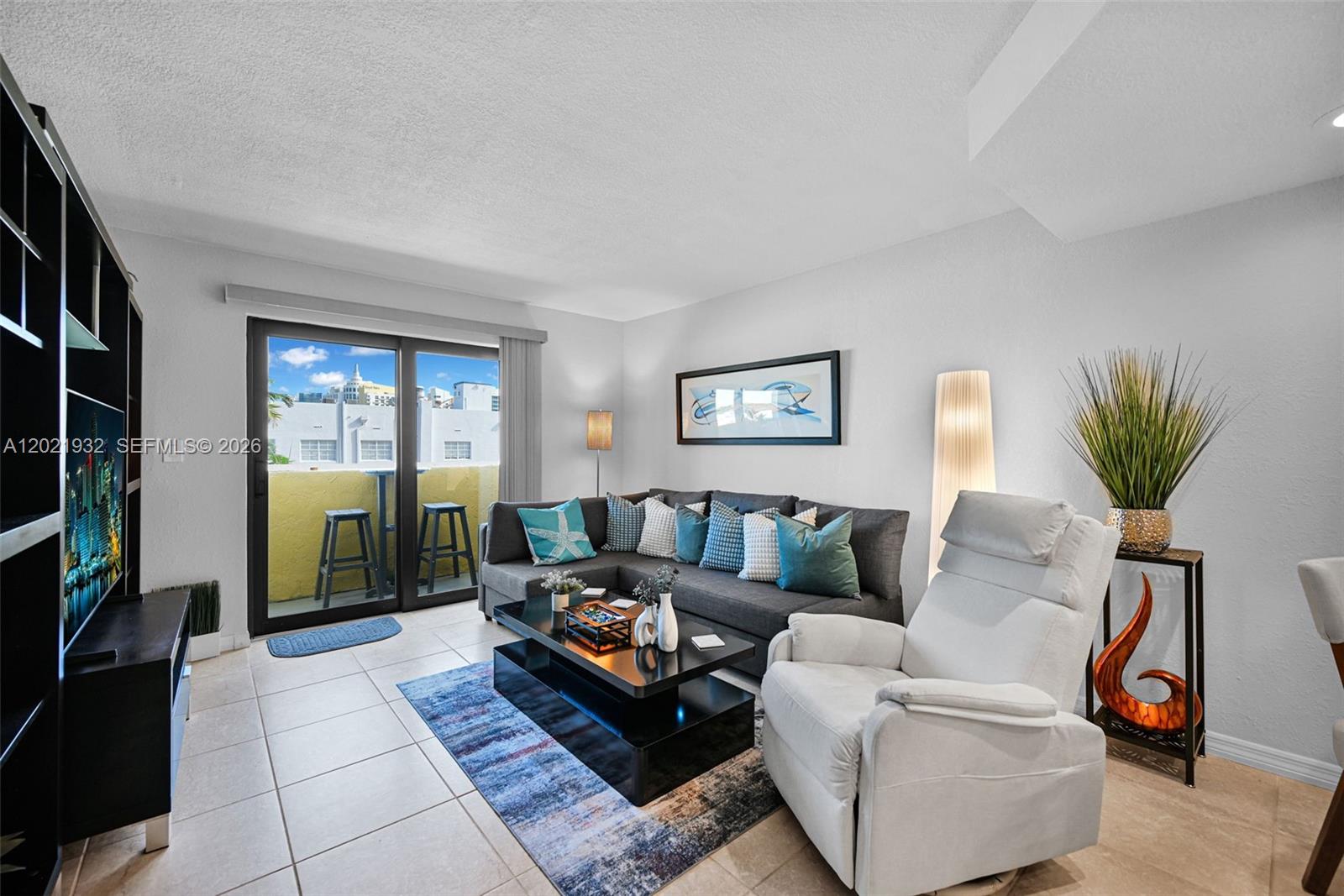 A living room features a gray sectional sofa, white recliner, coffee table, and balcony access — 1334 Collins Ave # 403, Miami Beach FL 33139, MIAMI BEACH, FL