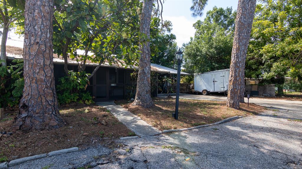 A single-story house with a screened porch, tall pine trees, and a trailer parked nearby — 2110 PALM TERRACE, SARASOTA, FL