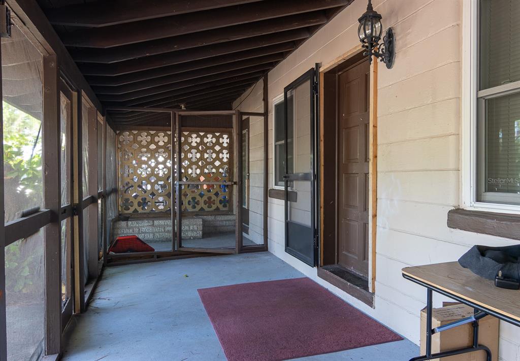 A screened-in porch features a concrete floor, a brown door, and decorative lattice wall panels — 2110 PALM TERRACE, SARASOTA, FL