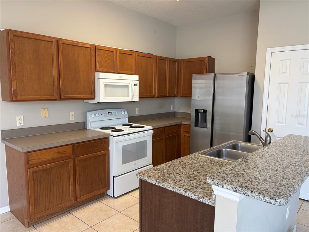 An empty room with light-colored tile flooring, gray walls, a ceiling fan, and a chandelier — 13508 BLUE SUNFISH COURT, RIVERVIEW, FL