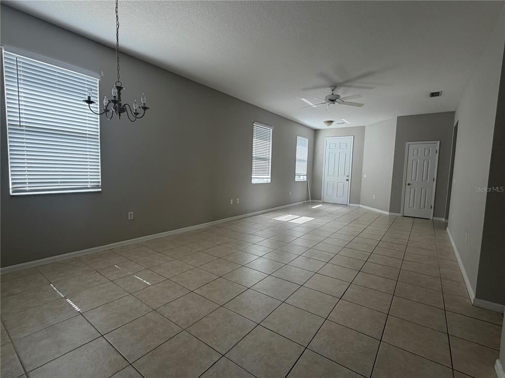 An empty room with light-colored tile flooring, gray walls, a ceiling fan, and a window — 13508 BLUE SUNFISH COURT, RIVERVIEW, FL