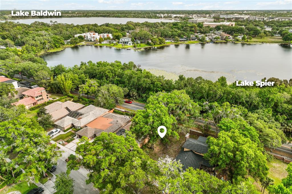 An aerial view shows a residential property with a house, trees, and nearby lakes — JESSICA COURT, WINTER PARK, FL
