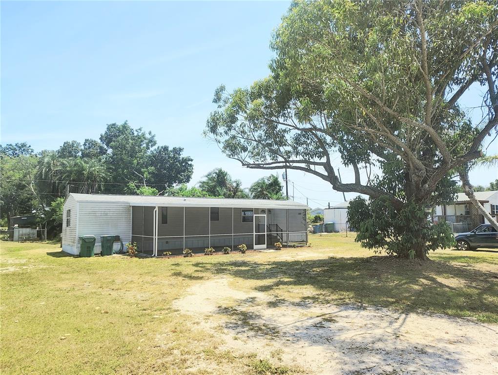 A single-story mobile home with a screened-in porch sits on a grassy lot — 6619 ORANGE BLOSSOM LANE, PUNTA GORDA, FL