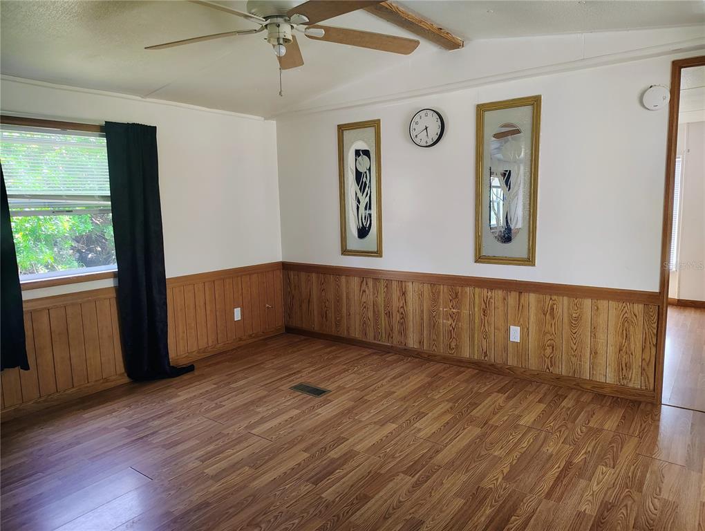 A room with wood-look flooring, wood wainscoting, a ceiling fan, and two framed wall art pieces — 6619 ORANGE BLOSSOM LANE, PUNTA GORDA, FL