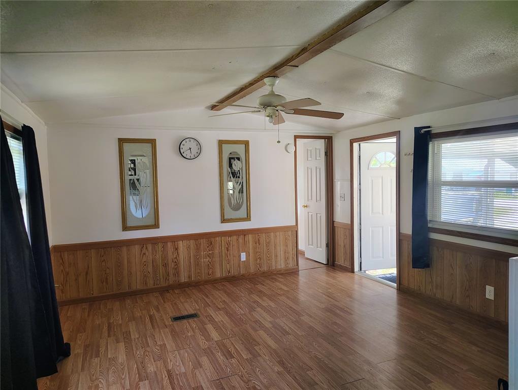 A living room with wood-look flooring, wood wainscoting, a ceiling fan, and an exterior door — 6619 ORANGE BLOSSOM LANE, PUNTA GORDA, FL