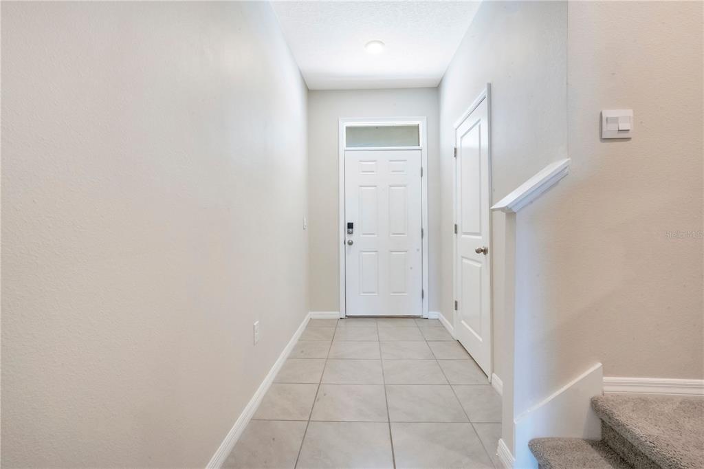 A tiled entryway features a white front door, a side closet, and carpeted stairs — 5359 PINECONE COURT, WILDWOOD, FL