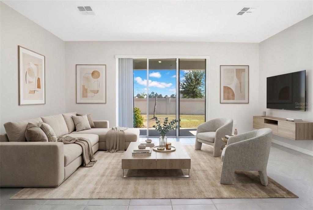 A living room features a beige sectional, two armchairs, a coffee table, and sliding glass doors — 5359 PINECONE COURT, WILDWOOD, FL