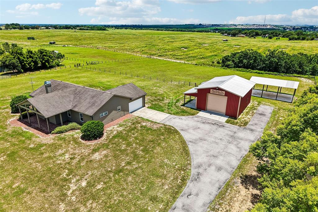 An aerial view shows a house, a red detached garage, and a carport on land — 3670 LAKE HATCHINEHA ROAD, HAINES CITY, FL