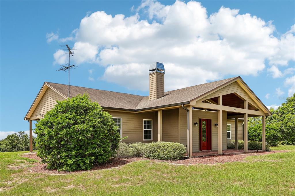 A tan house with a red front door and a chimney under a blue sky — 3670 LAKE HATCHINEHA ROAD, HAINES CITY, FL