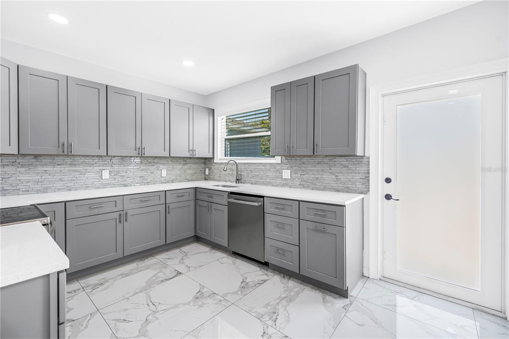 A kitchen with gray cabinets, white countertops, a tiled backsplash, and white marble-patterned floor tiles — 1827 16TH STREET S, ST PETERSBURG, FL