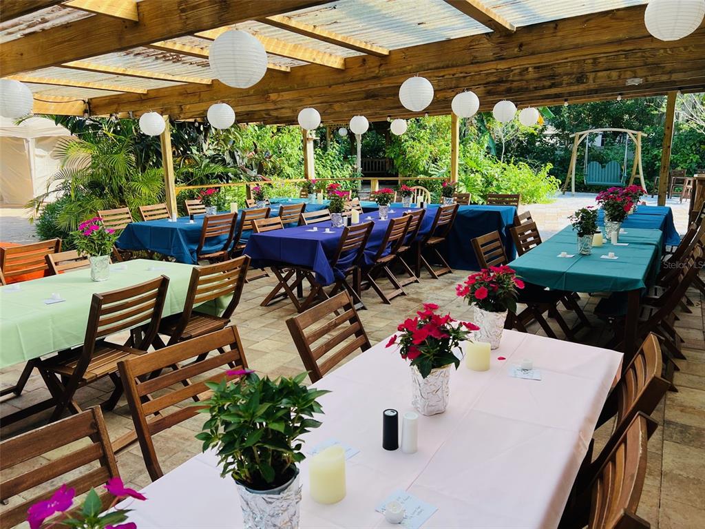 An outdoor patio features multiple tables with colorful tablecloths, potted flowers, and hanging paper lanterns — 5909 MOHR ROAD, TAMPA, FL