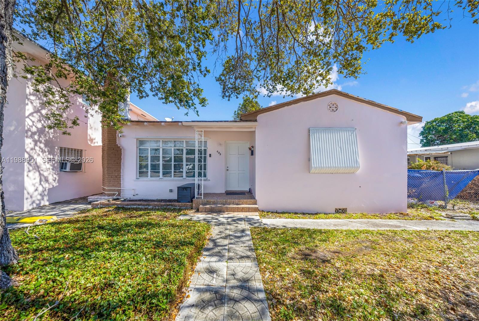 A single-story pink house features a front walkway, a large window, and a metal awning — 605 NW 34th Ave, Miami FL 33125, MIAMI, FL