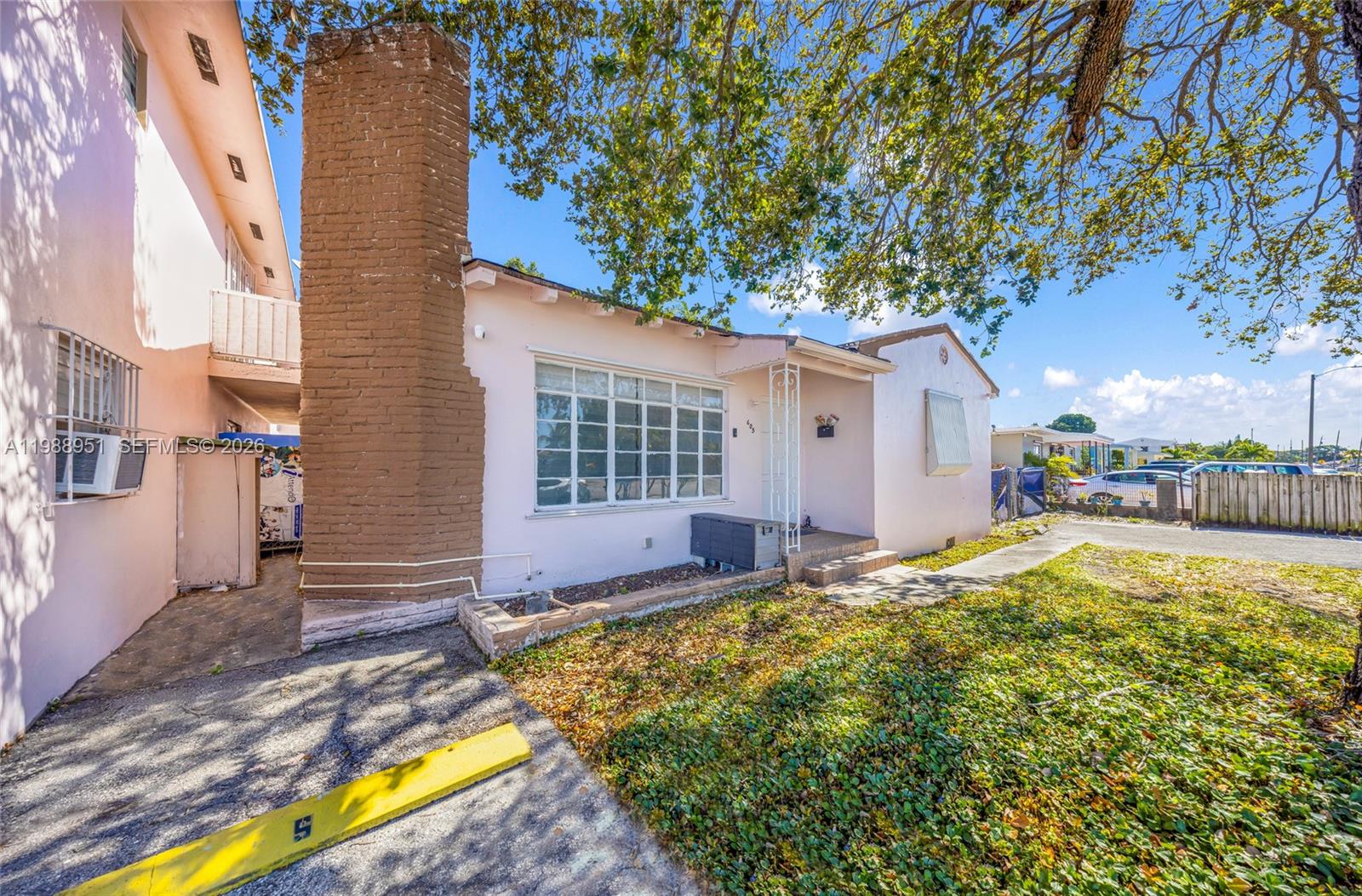 A pink single-story house features a prominent brick chimney and a small front porch — 605 NW 34th Ave, Miami FL 33125, MIAMI, FL