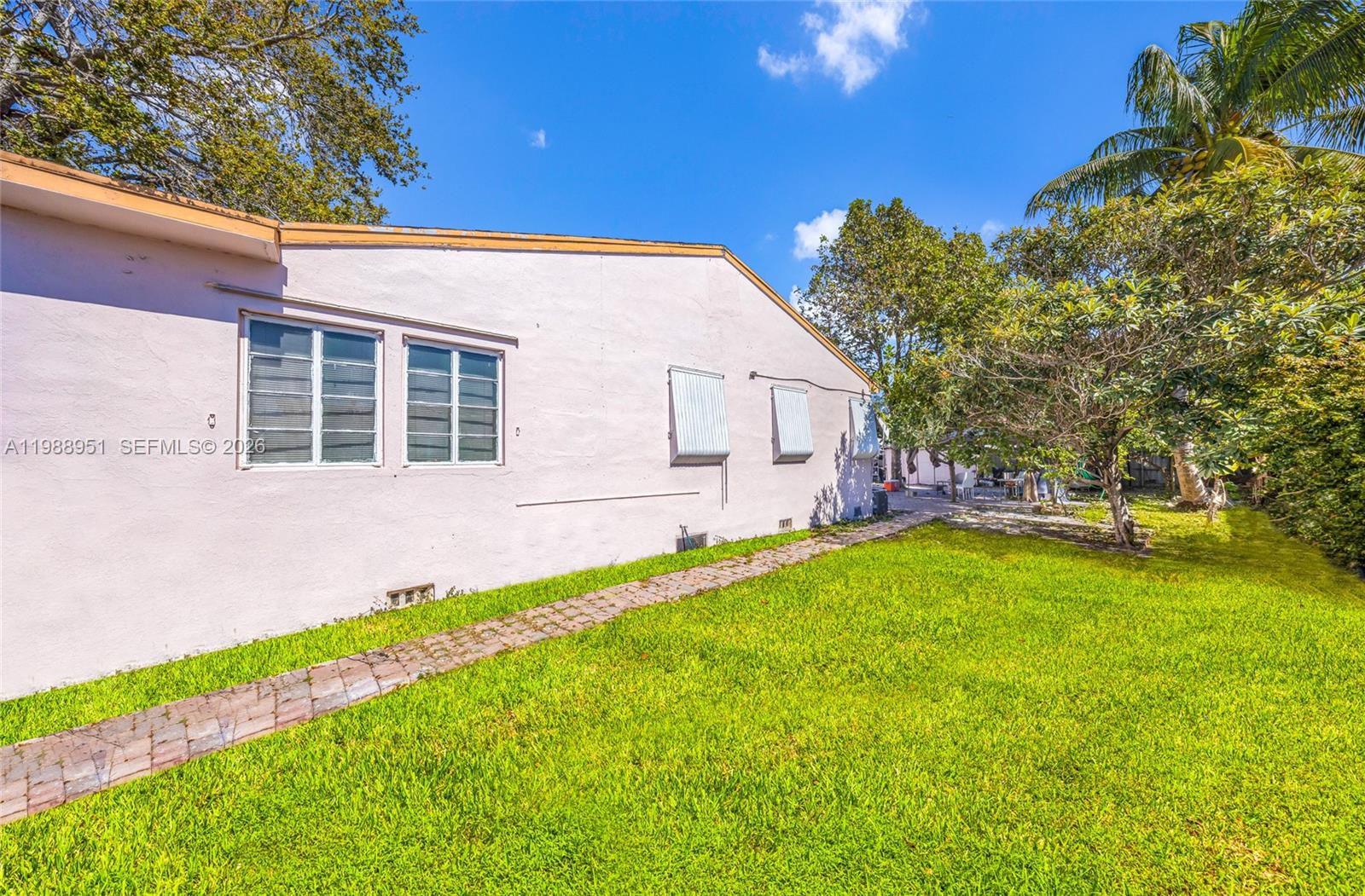 The exterior of a light-colored house features a brick walkway and a grassy yard — 605 NW 34th Ave, Miami FL 33125, MIAMI, FL