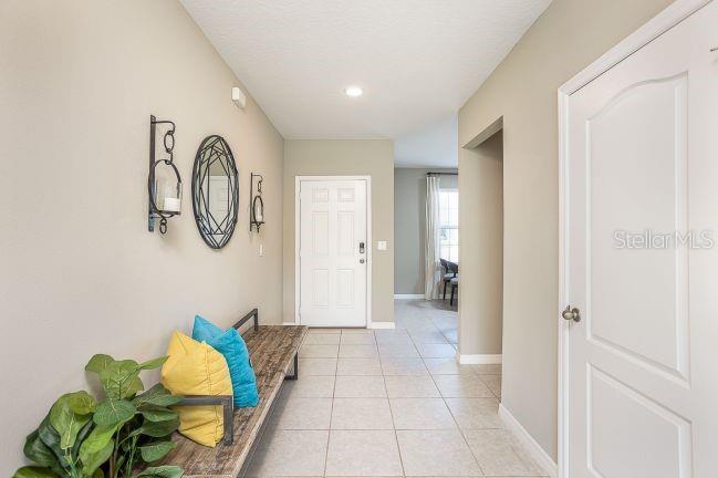 A tiled entryway features a wooden bench with colorful pillows, wall decor, and a white door — 621 BROADOAK DRIVE, DUNDEE, FL