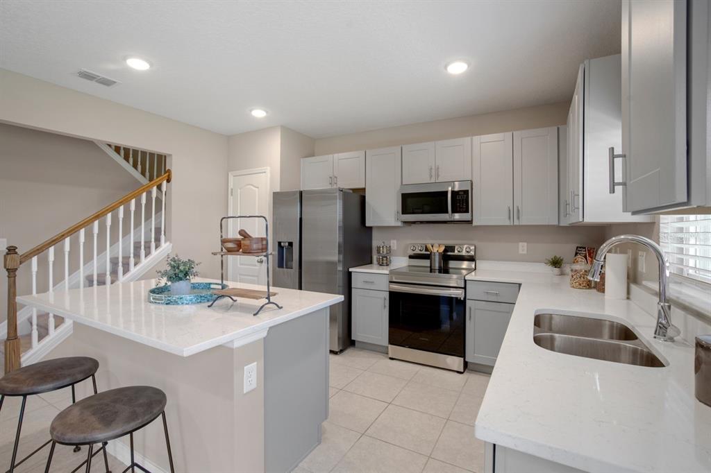 A kitchen with gray cabinets, stainless steel appliances, white countertops, and a central island — 621 BROADOAK DRIVE, DUNDEE, FL
