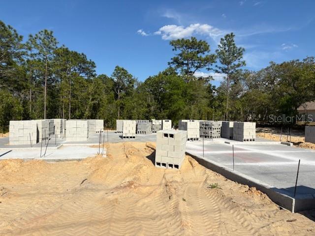 A newly constructed house with a two-car garage sits on a sandy, undeveloped lot — 5535 SW 121ST TERRACE, OCALA, FL