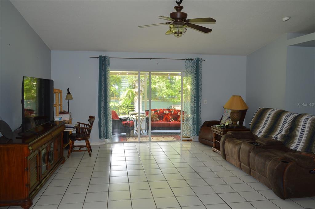 A living room with white tile floors, a ceiling fan, and sliding glass doors to a patio — 2308 PALM AVENUE, SEFFNER, FL