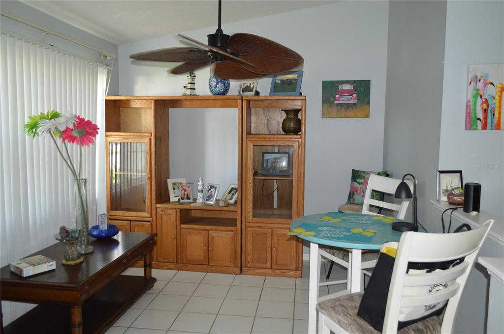 A living and dining area features a wooden entertainment center, tile flooring, and a ceiling fan — 2308 PALM AVENUE, SEFFNER, FL