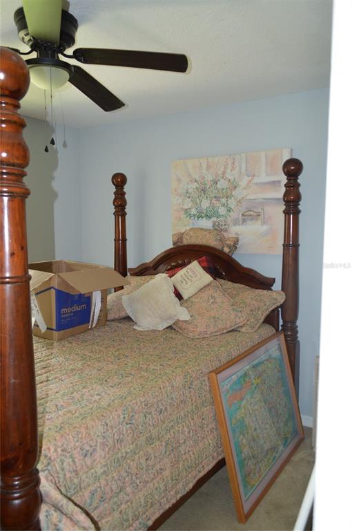 A bedroom features a wooden four-poster bed, a ceiling fan, and a floral wall canvas — 2308 PALM AVENUE, SEFFNER, FL