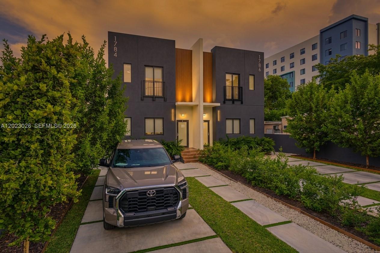 A modern two-story duplex with dark gray siding and a concrete driveway featuring a parked truck — 1784 & 1786 NW 31st St, Miami FL 33142, MIAMI, FL