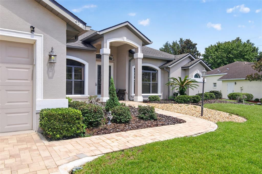 A beige house exterior features a paved walkway, a garage, and a covered entryway — 6535 SW 51ST TERRACE, OCALA, FL