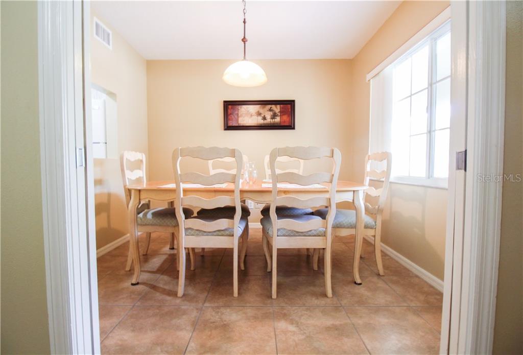 A dining room with a wooden table, four chairs, tile flooring, and a pendant light — 4457 45TH AVENUE W UNIT 110, BRADENTON, FL