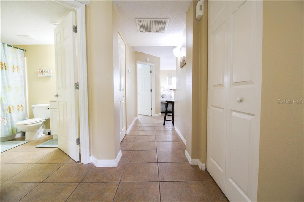A hallway with tile flooring leads to a bathroom and a bedroom — 4457 45TH AVENUE W UNIT 110, BRADENTON, FL