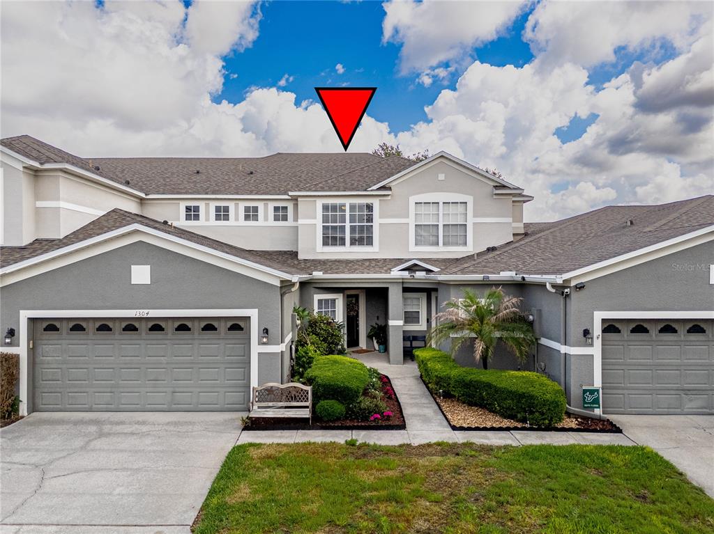 The exterior of a two-story residential building features gray stucco walls and a shingled roof — 1304 SANDSTONE RUN, SANFORD, FL