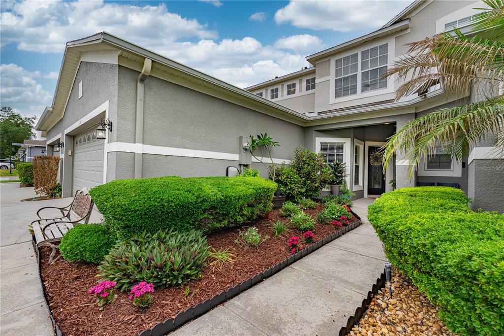 The exterior of a two-story house features a garage, a landscaped garden, and a walkway — 1304 SANDSTONE RUN, SANFORD, FL