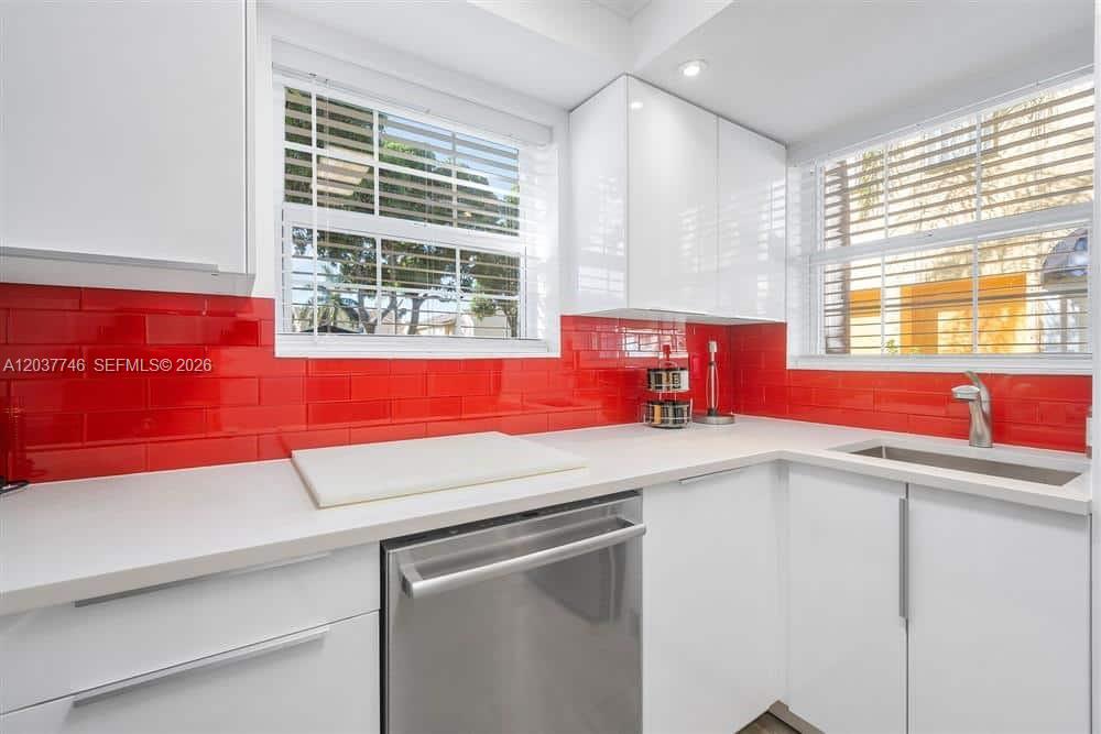 A kitchen features white cabinets, a red subway tile backsplash, and stainless steel appliances — 234 Waterside Dr # 234, Hypoluxo FL 33462, HYPOLUXO, FL