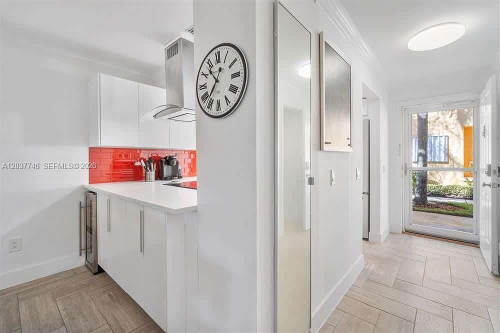 A kitchen features white cabinetry, a red tile backsplash, and a wall-mounted clock — 234 Waterside Dr # 234, Hypoluxo FL 33462, HYPOLUXO, FL
