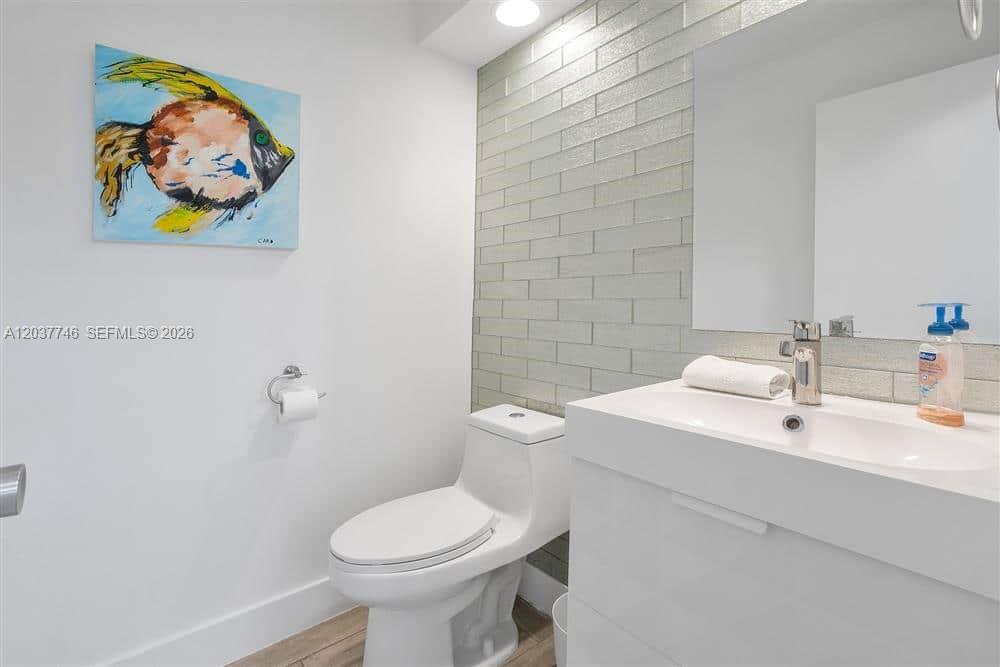 A modern bathroom features a white toilet, a vanity with a sink, and tiled walls — 234 Waterside Dr # 234, Hypoluxo FL 33462, HYPOLUXO, FL